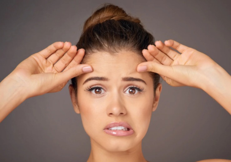 donna con le dita sulla fronte che fa una smorfia