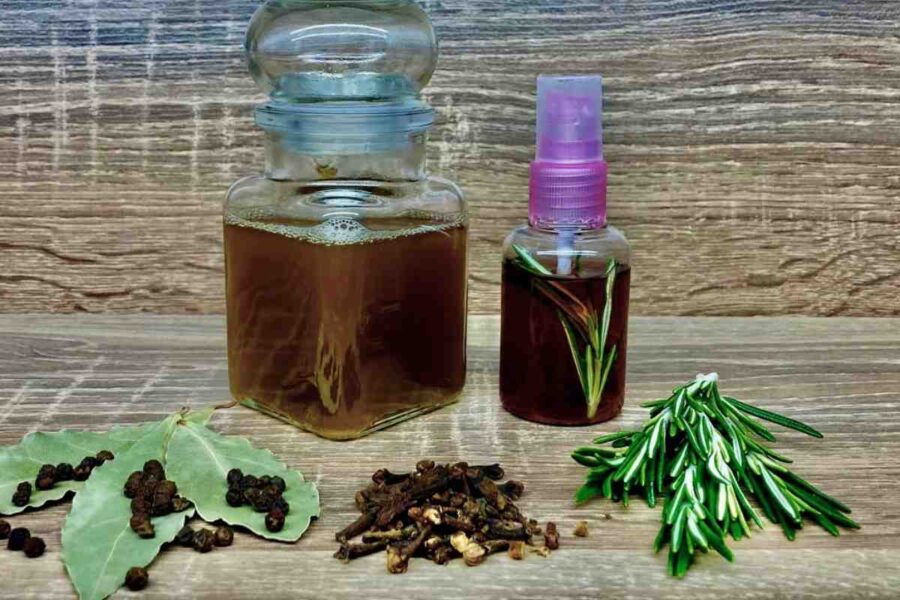 foglie di alloro, chiodi di garofano, rosmarino, piselli al pepe e contenitori con liquido