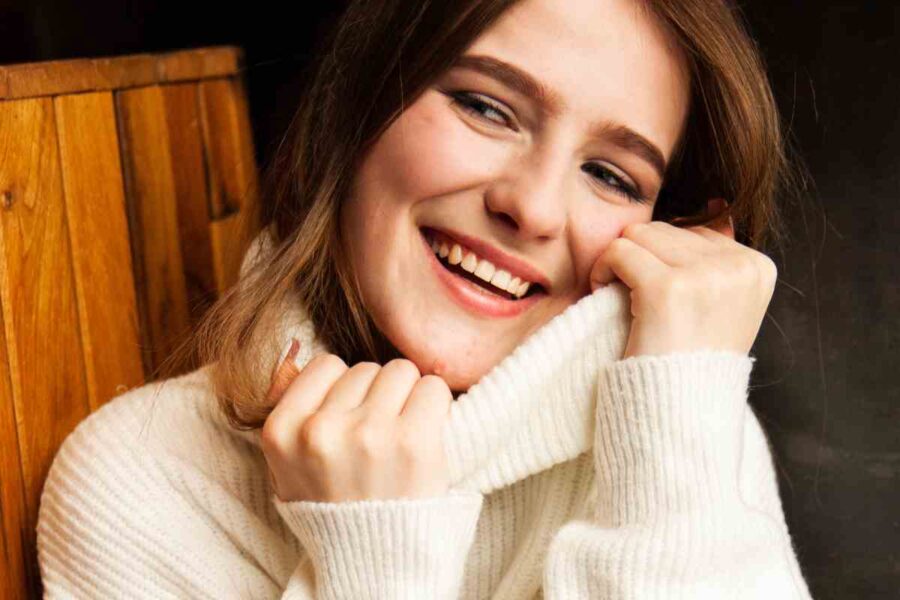 ragazza sorridente stringe la sua maglia a collo alto