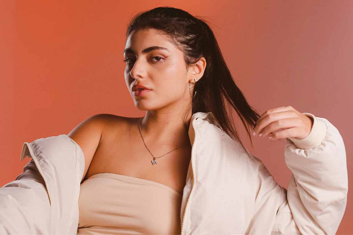 una ragazza indossa un piumino corto su un top senza spalline