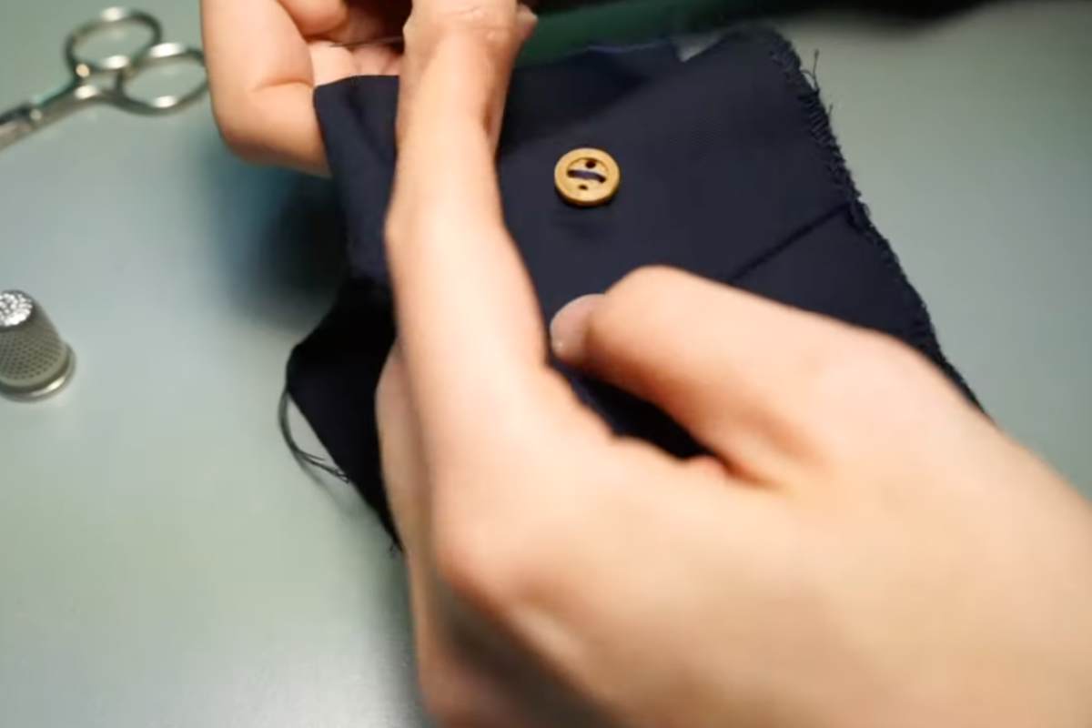 persona attacca bottone su un ritaglio di tessuto