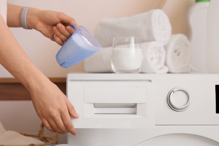 persona che mette detersivo in lavatrice