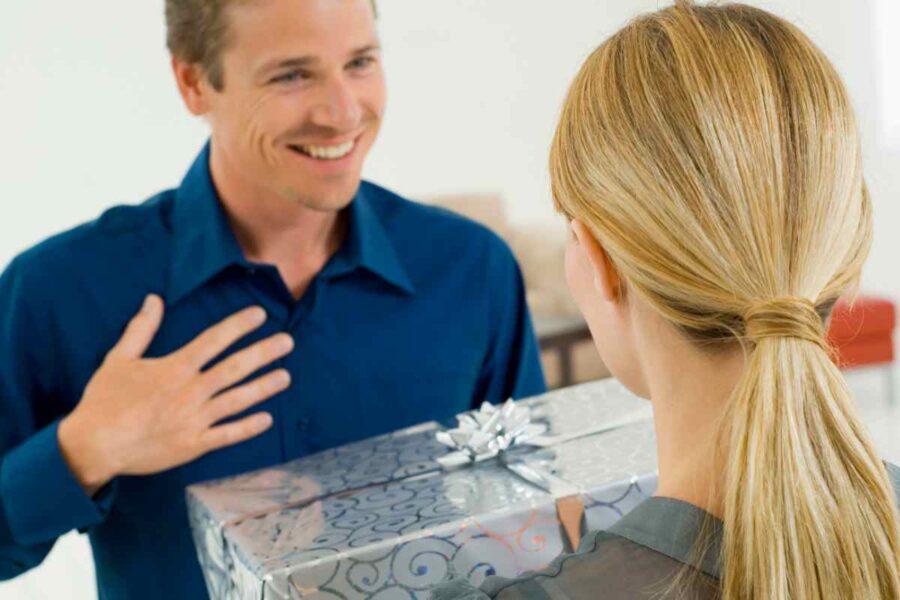 donna di spalle dona un pacco regalo a un uomo sorridente