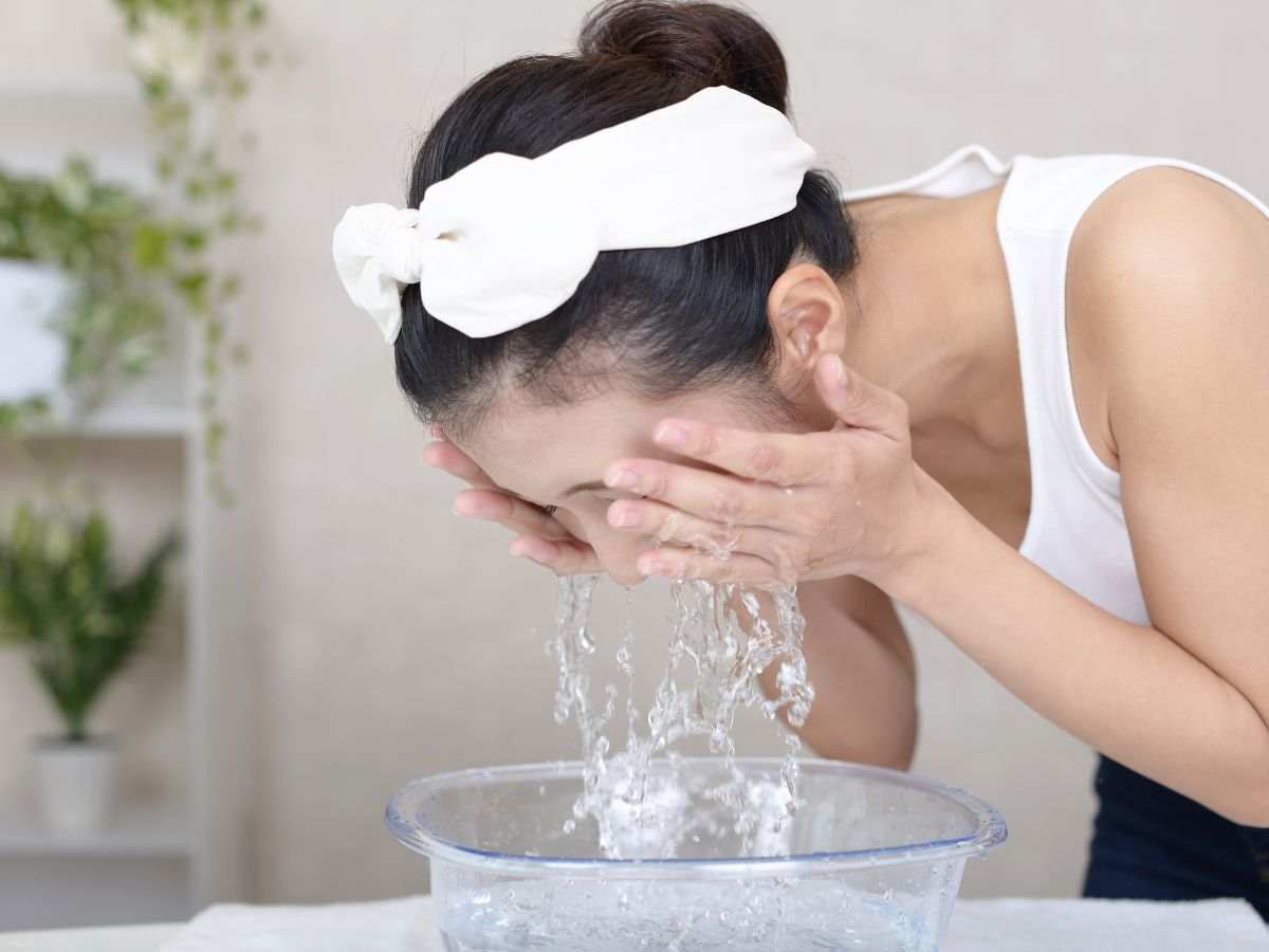 donna asiatica sciacqua viso da una bacinella