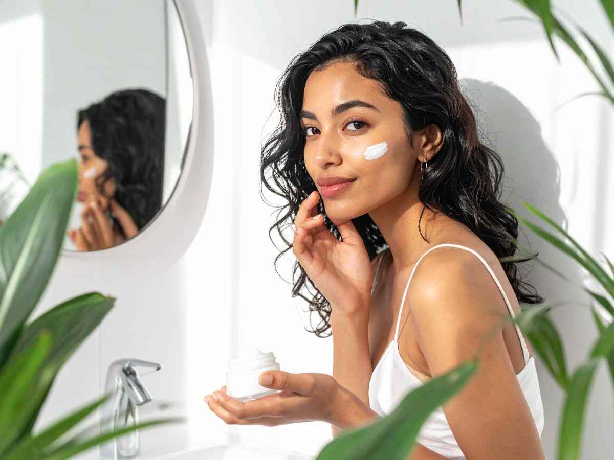 ragazza allo specchio mette crema sul viso