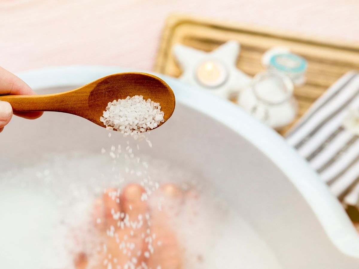 piedi a bagno in una bacinella e sale grosso in un cucchiaino